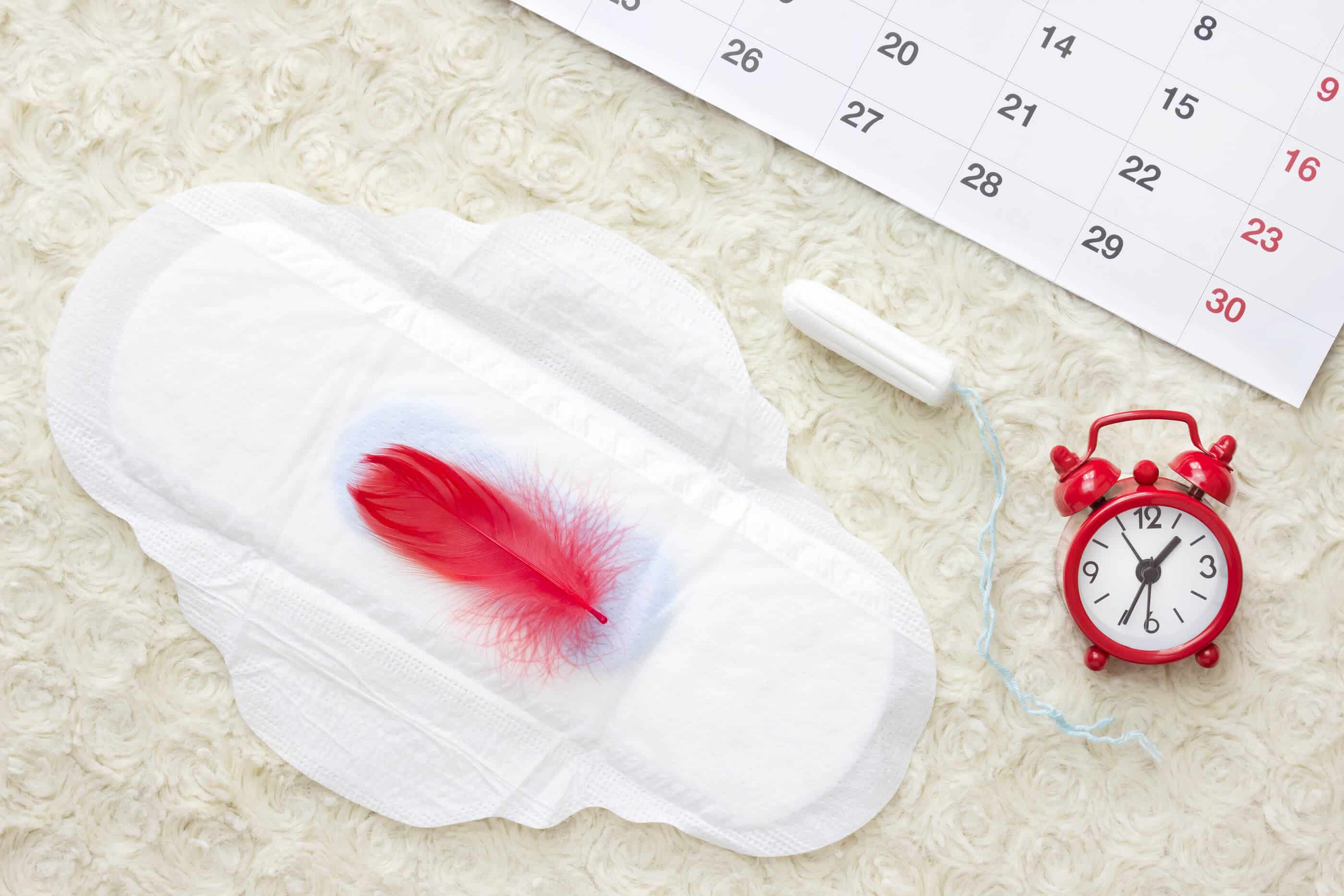 a pad with blood in the middle next to a stopwatch, piece of chalk, and calendar
